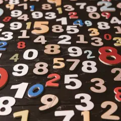 Kolorowe cyferki rozsypane na czarnym tle. Wśród nich widać 8, 9, 10, 25. Jaka jest największa liczba?