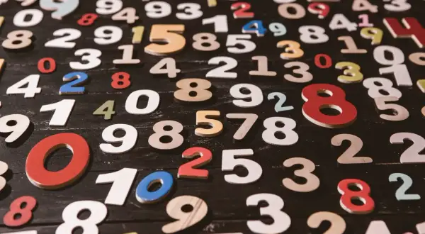 Kolorowe cyferki rozsypane na czarnym tle. Wśród nich widać 8, 9, 10, 25. Jaka jest największa liczba?